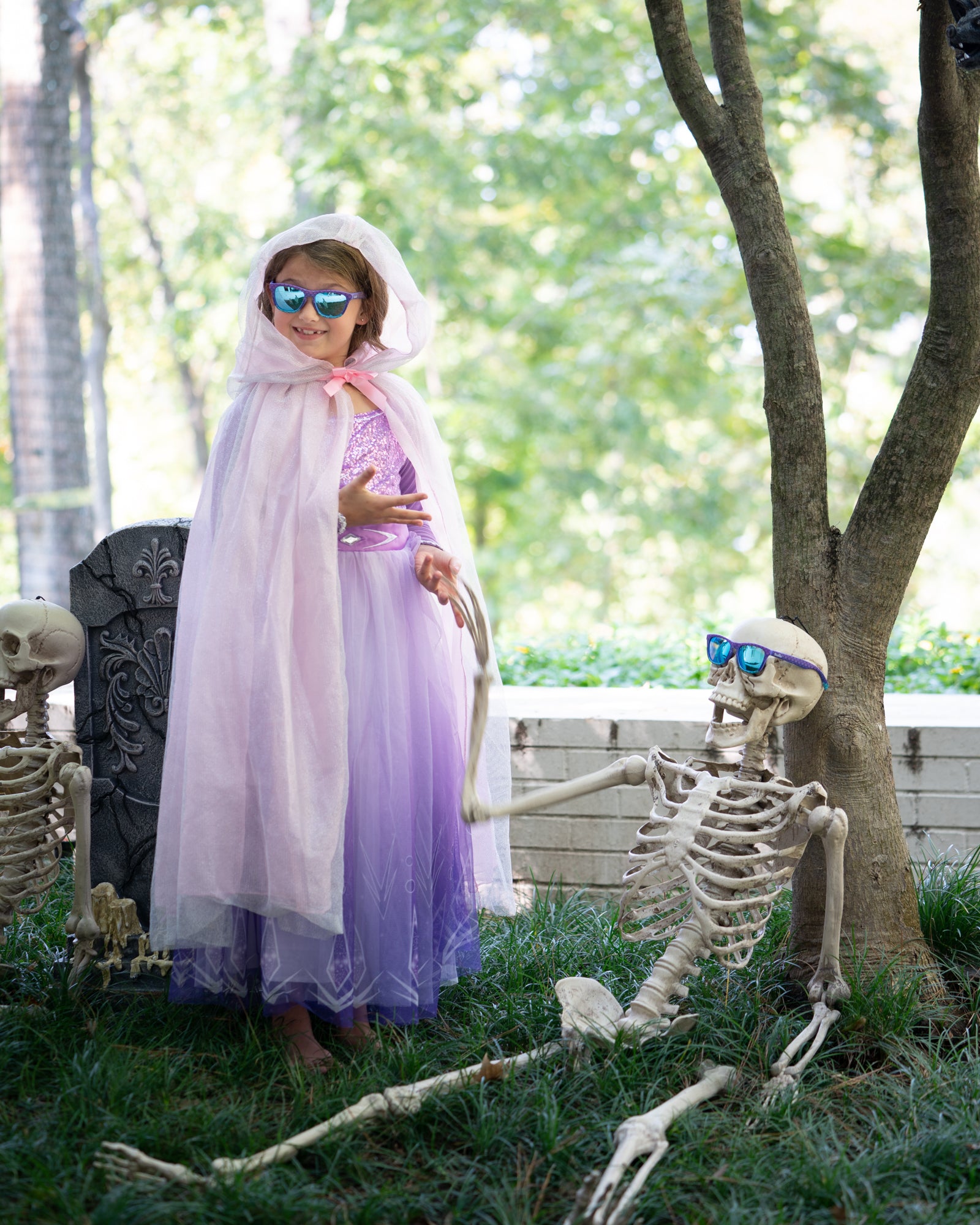 Little girl wearing a purple princess costume and matching polarized kids sunglasses in Be Yourself, Unless you can be a mermaid sunnies shades in a mainly purple mermaid scale frame and polarized reflective blue lenses.