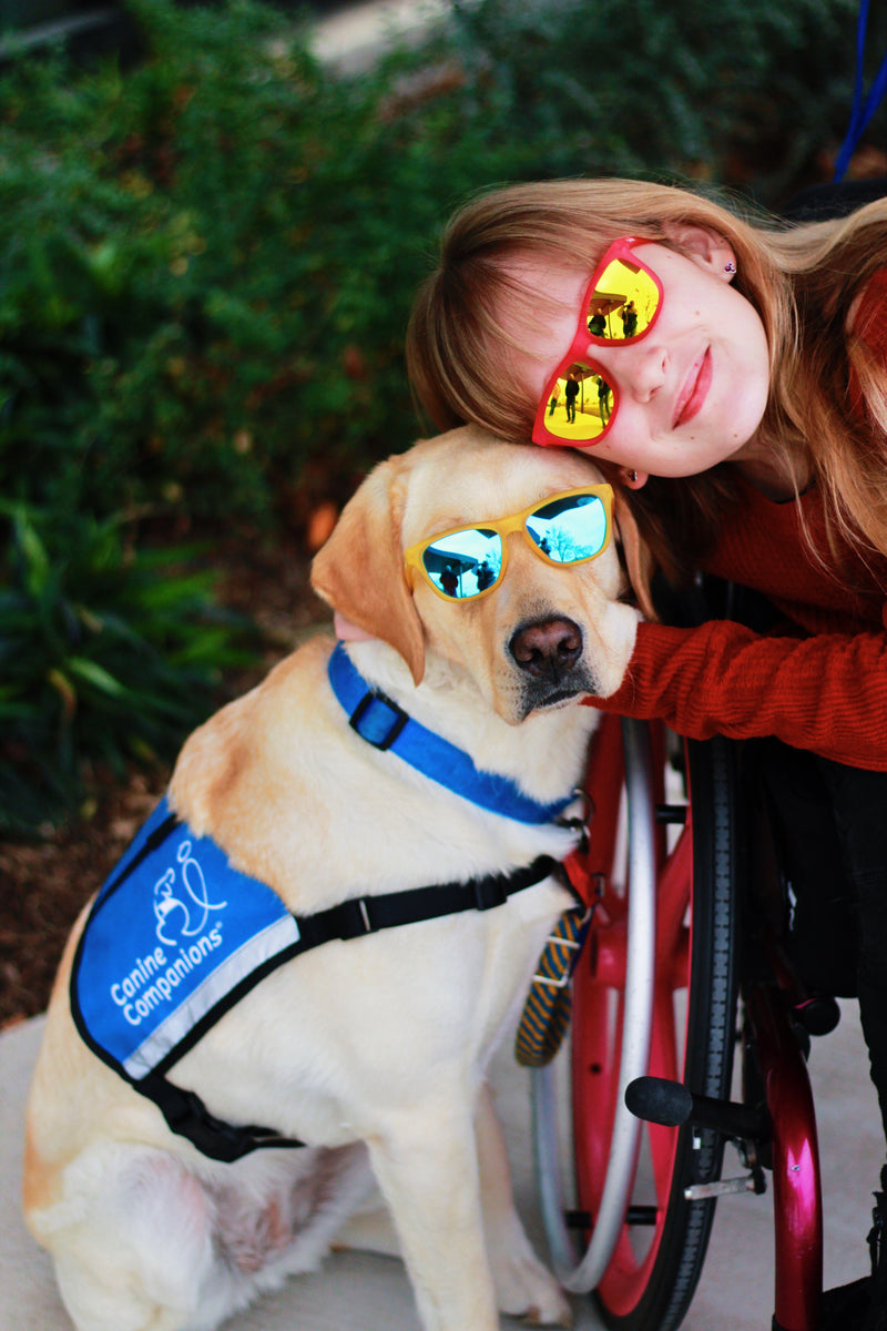 Little girl wearing Sunnies with her service dog from Canine Companions who is also wearing Sunnies polarized kids sunglasses