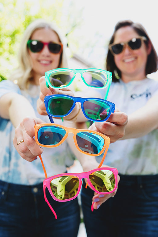 Co Founders, Kim and Courtney, holding up their best selling solid kids polarized sunglasses