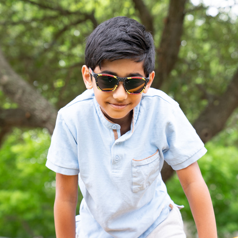 Boy wearing coral snake printed kids polarized sunglasses by sunnies shades.