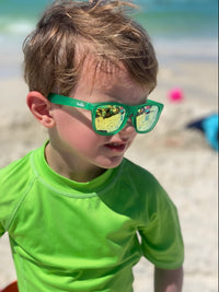 Little boy wearing polarized green sunnies at the beach with 100% UVA/UVB protection and an anti-slip material on the frame.