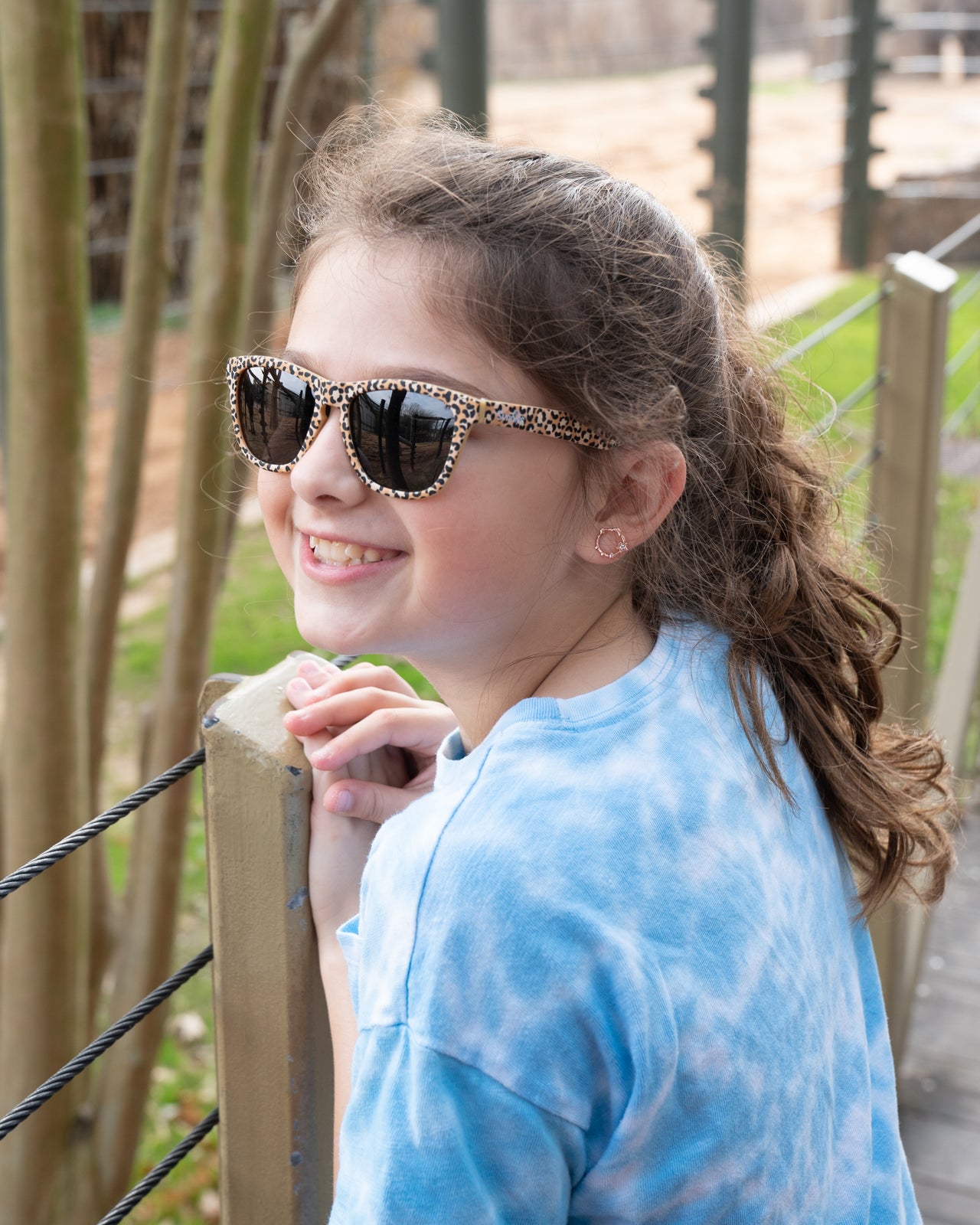 Little girl wearing a pair of kids sunglasses in a leopard print by Sunnies with polarized lenses and black non reflective lens