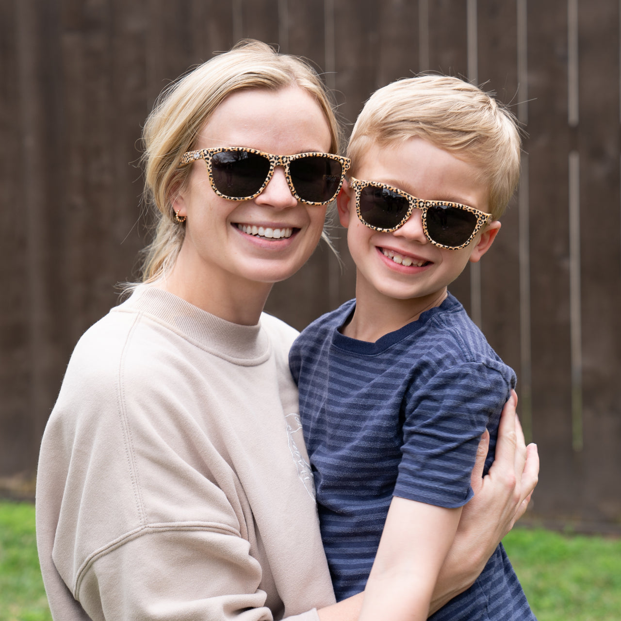 Mother and son wearing matching sunnies in a leopard print with polarized lenses and 100% UVA/UVB protection