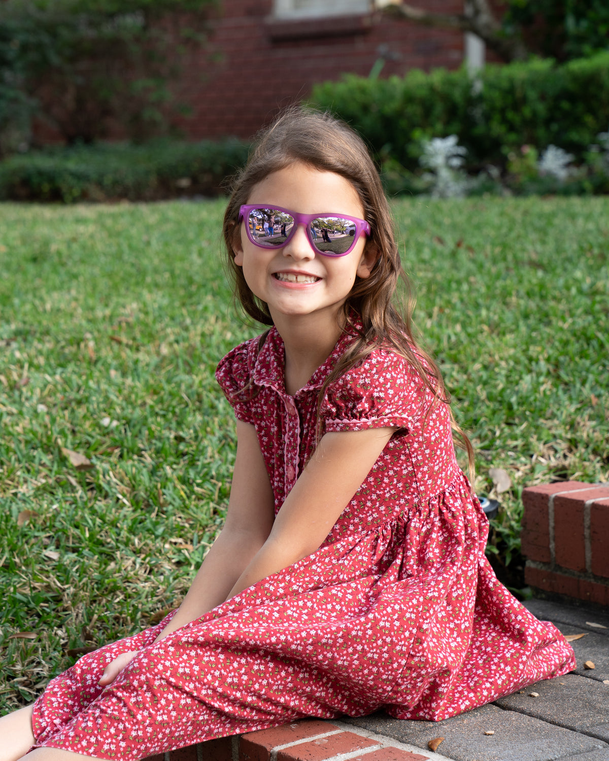 Little girl wearing sunnies shades polarized kids sunglasses in a transparent purple frame and purple reflective lenses.