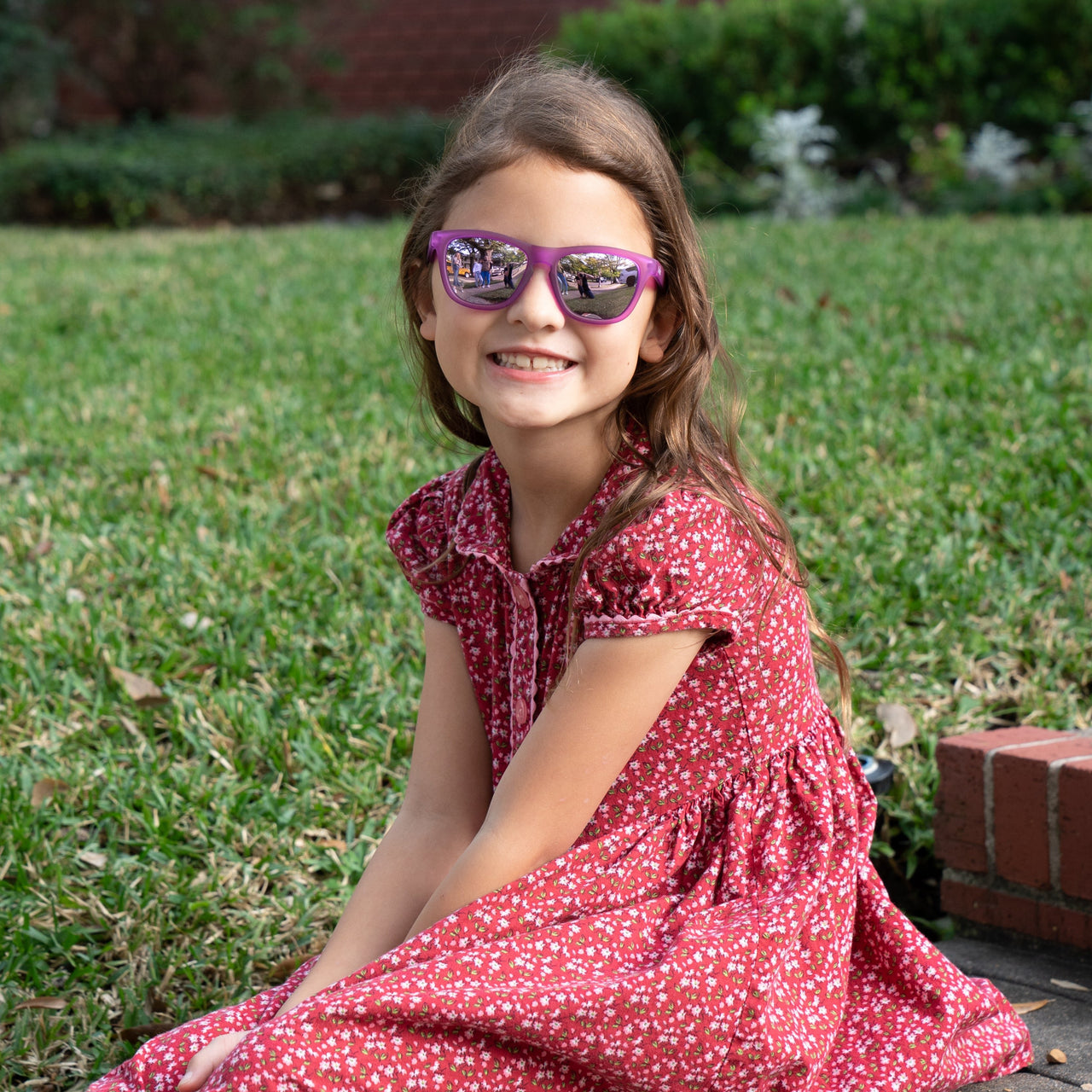 Little girl wearing sunnies shades polarized kids sunglasses in a transparent purple frame and purple reflective lenses.