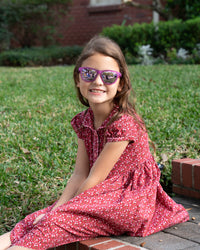 Thumbnail for Little girl wearing sunnies shades polarized kids sunglasses in a transparent purple frame and purple reflective lenses.