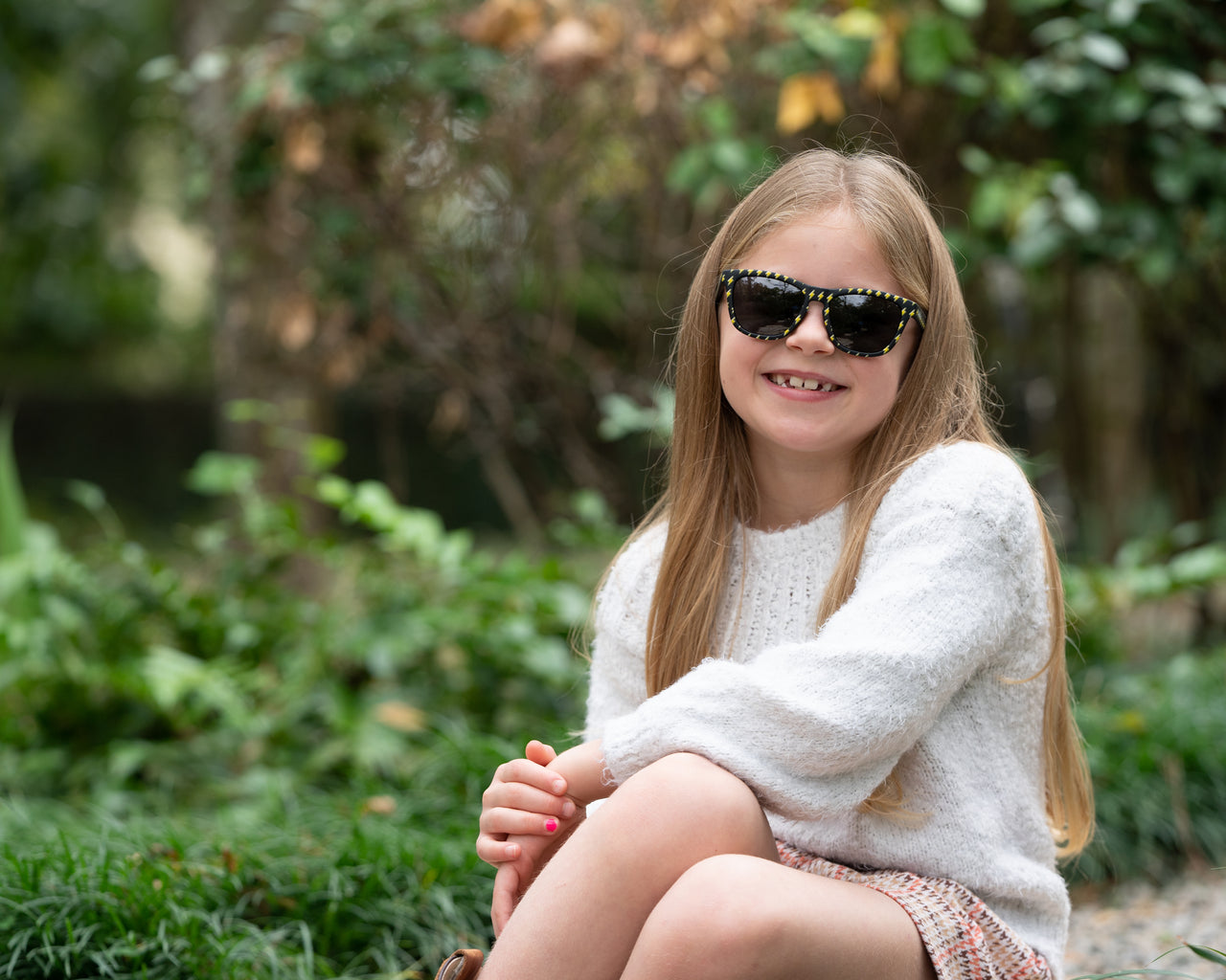 Little girl wearing polarized sunnies shades kids sunglasses in a black frame with lightning bolts and non-reflective black lenses.