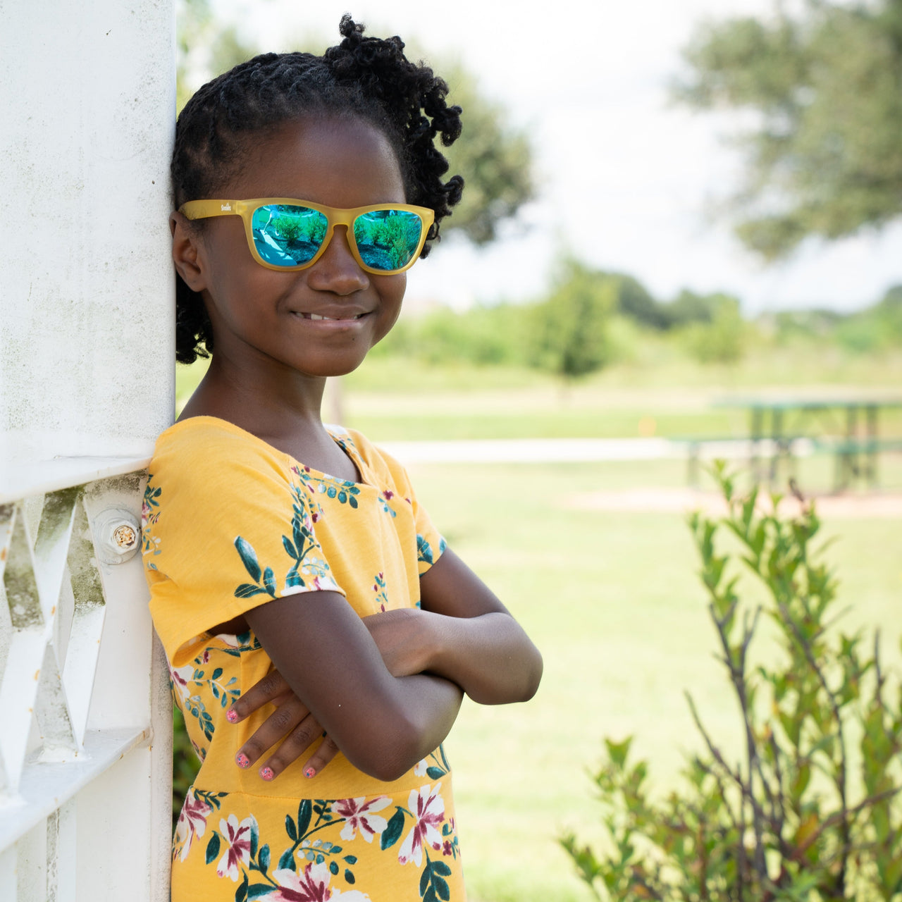 Little girl wearing sunnies shades polarized kids sunglasses in a transparent yellow frame with reflective blue lenses.