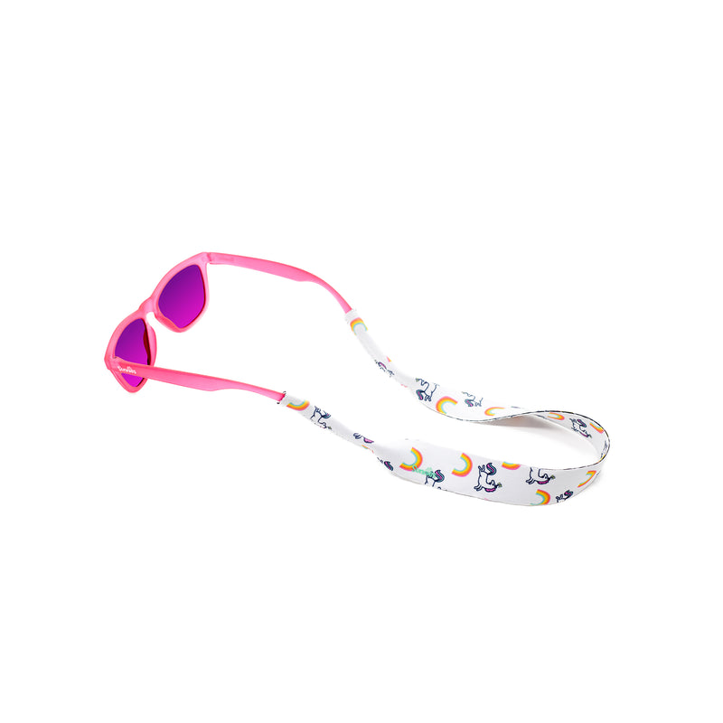Kids sunglass strap in a unicorn and rainbow print attached to a pair of sunnies kids sunglasses in pink